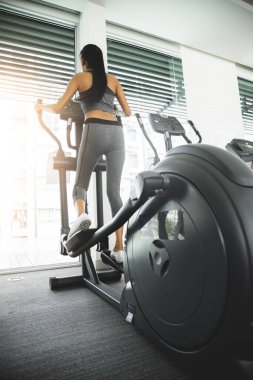 Asyalı kadın spor salonunda eliptik eğitmen makinede egzersiz.