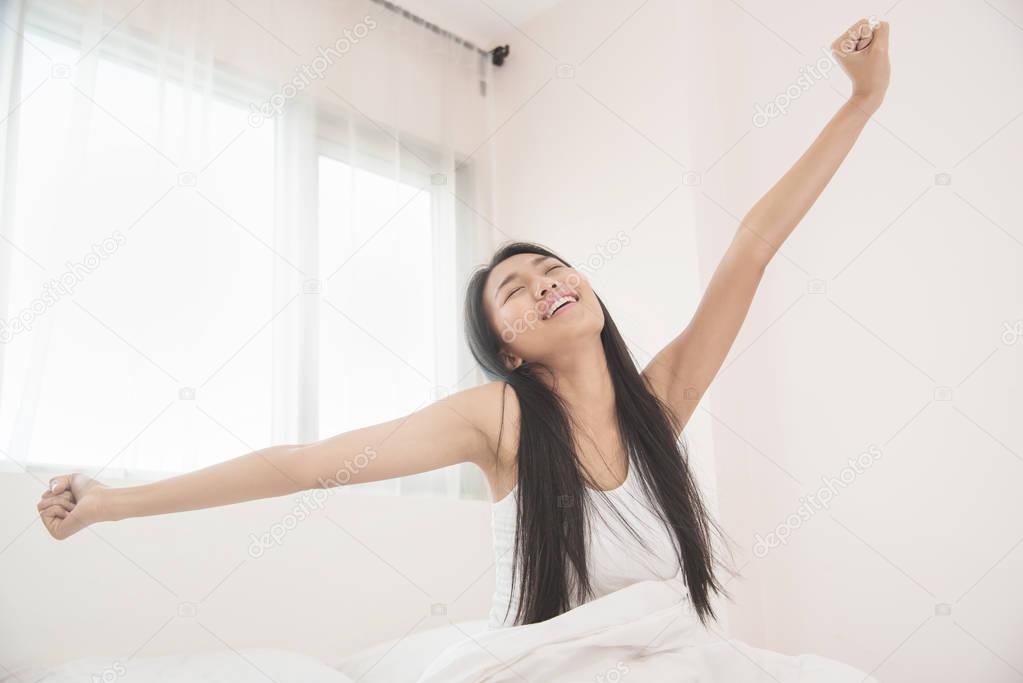 Beautiful Asian woman waking up on her bed in the morning. Happi