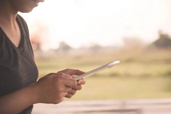 Asijská dívka pomocí tabletu nebo smartphonu na pozadí krajiny. — Stock fotografie