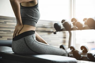 Sonra spor salonunda egzersiz sırt ağrısı olan genç kadın.
