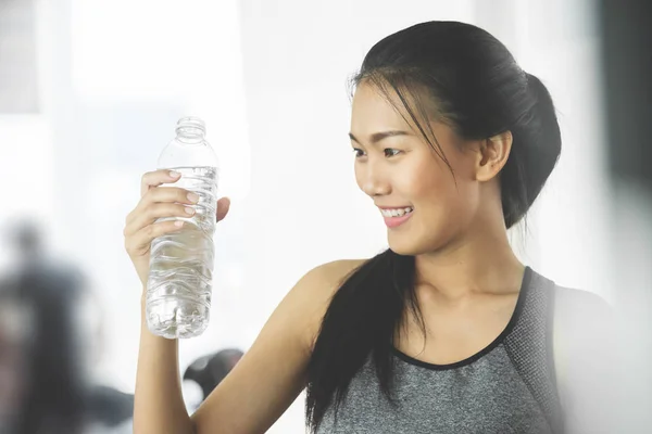 Азиатка в спортивной одежде держит бутылку воды в спортзале . — стоковое фото