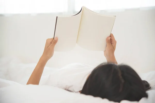 Uvolněné asijské dívka s knihou na posteli. — Stock fotografie