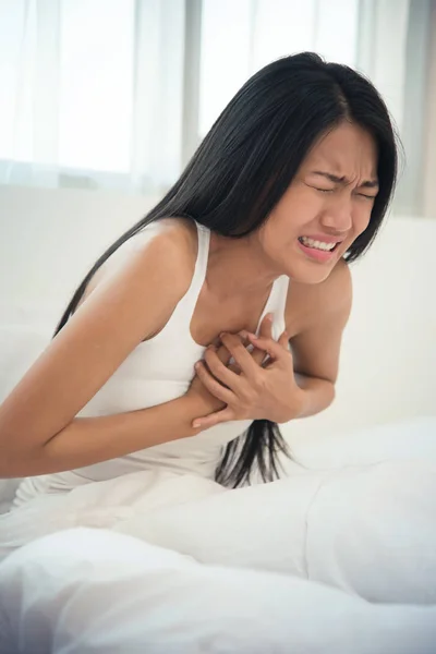 Mujer asiática teniendo un ataque al corazón en su cama. espacio de copia . — Foto de Stock