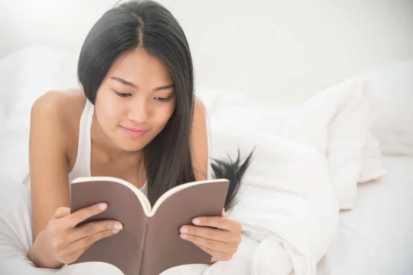 Entspannt asiatische Mädchen lesen ein Buch auf ihrem Bett. — Stockfoto