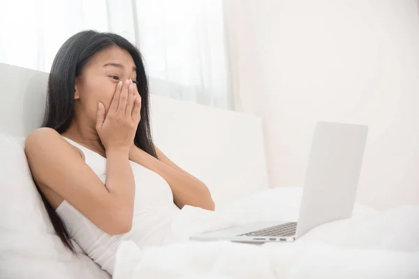 Happiness Asian woman with laptop on her bed.