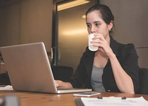 Empresária bebendo água enquanto trabalhava com laptop no o — Fotografia de Stock