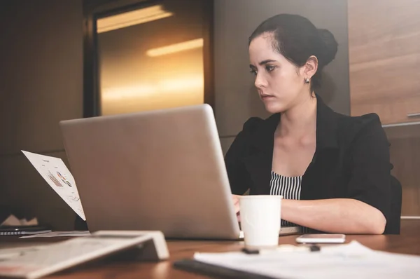 Empresária olhando para documentos de negócios enquanto ela usando lapt — Fotografia de Stock