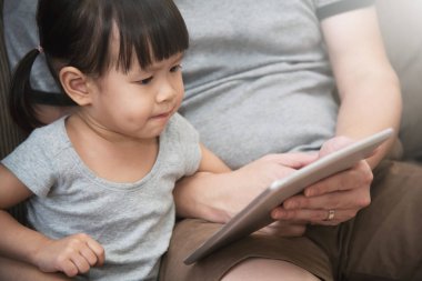 Asyalı çocuk ve onu oturan ve kullanma dijital tablet baba 