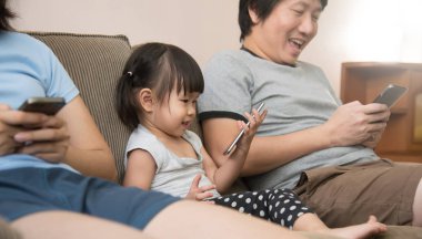 Asyalı kızı ve cep telefonu kullanarak aile.