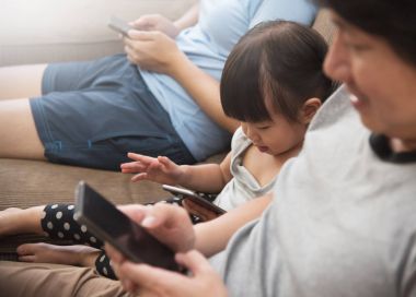 Asyalı kızı ve cep telefonu kullanarak aile.