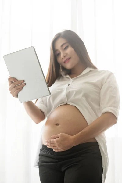 Asiatiska gravid kvinna använda digitala surfplatta. — Stockfoto