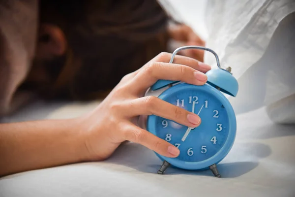 Сонная азиатка держит будильник . — стоковое фото