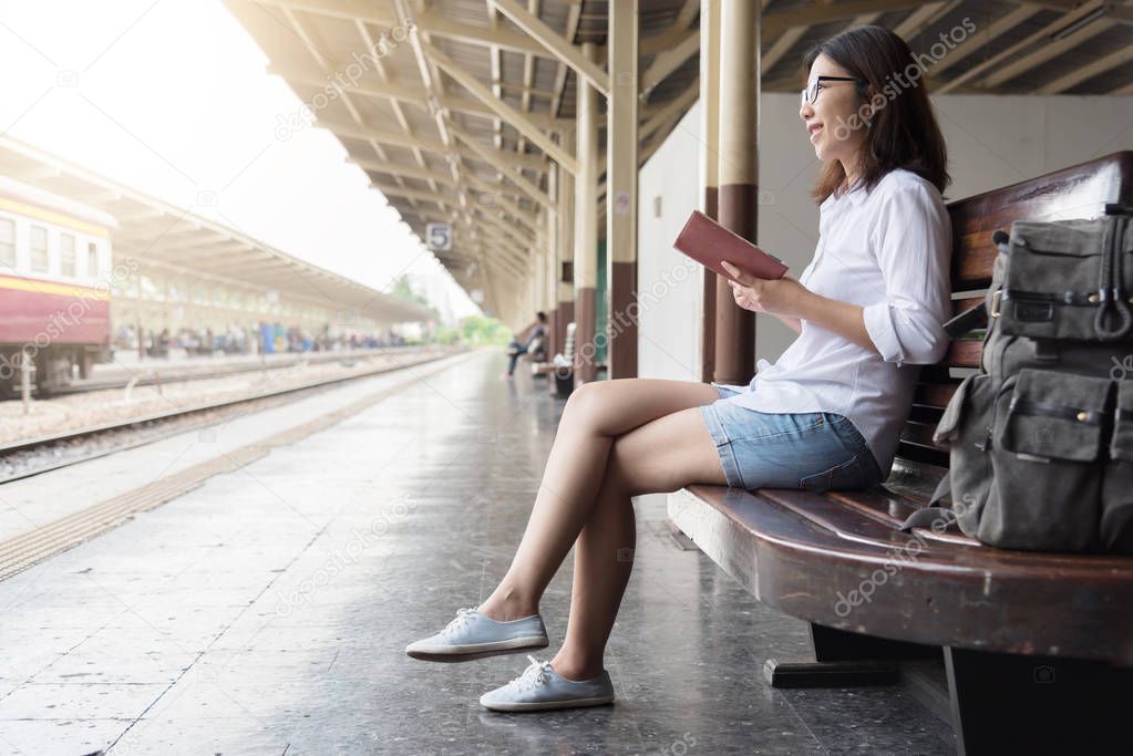 Asian Female backpacker is sitting at train station.