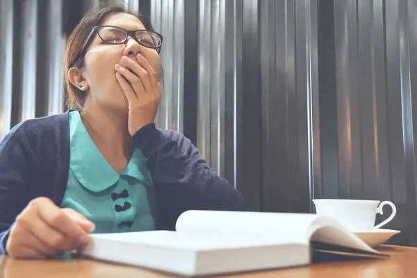 Сонная азиатка зевает во время чтения книги . — стоковое фото