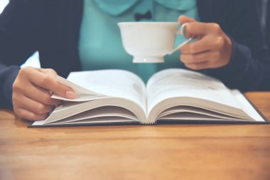 Kitap veya günlük okuma ve sıcak kahve içme kadın. 