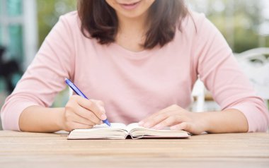 Kadın ve günlük ya da defter üzerinde yazılı.