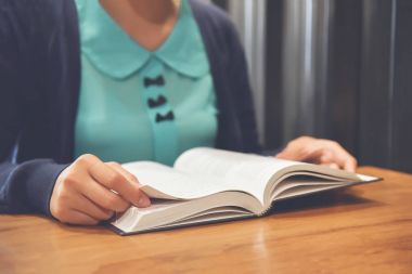 Asyalı kadın kitap veya günlük kahve dükkanında okuma. 