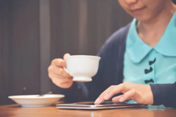 Азіатський жінка за допомогою планшетному ПК попиваючи каву. — стокове фото