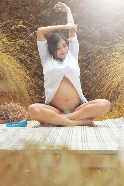 Unga gravid kvinna stretching på park. — Stockfoto