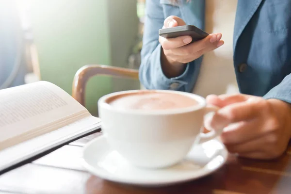 Жінка руки за допомогою смартфона і тримає чашку кави . — стокове фото