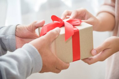Asyalı kadın kahverengi hediye kutusu yaşlı adama veriyor.