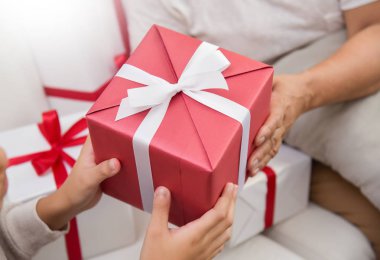 Asyalı çocuk kırmızı hediye kutusu yaşlı kadın için veriyor.