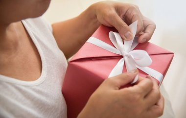 Kırmızı hediye kutusu beyaz şerit üzerinde tutan Asya yaşlı kadın. 