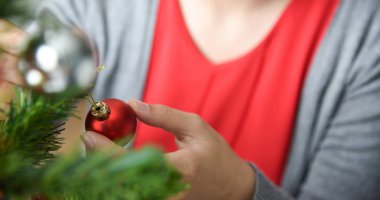 Asyalı kadın kırmızı topu ile Noel ağacı süsleme.