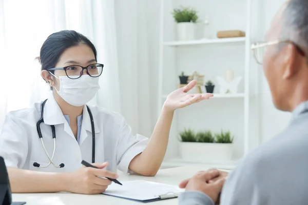 Азіатські жінки лікар говорить старший людина пацієнт. — стокове фото