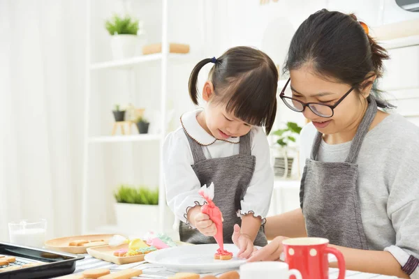 Asiático Kid e jovem mãe decorar biscoitos . — Fotografia de Stock