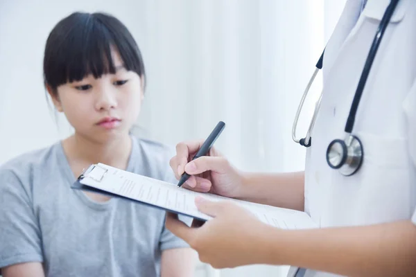 Médico tomando nota na lista de verificação para uma menina pacientes . — Fotografia de Stock