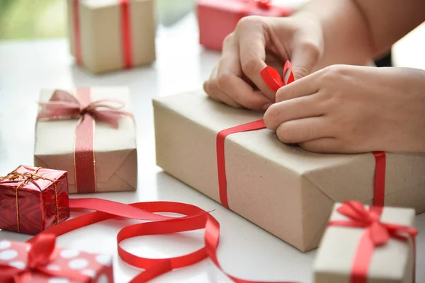 Frauenhände wickeln Geschenkboxen ein. — Stockfoto