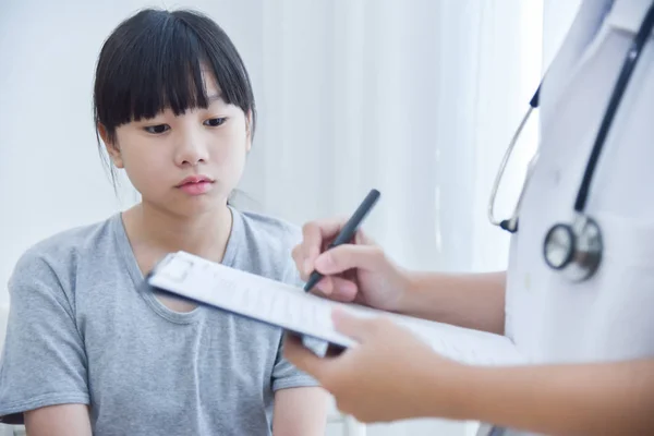 Médico tomando nota na lista de verificação para uma menina pacientes . — Fotografia de Stock