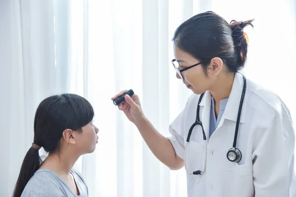 Dokter memakai kacamata memeriksa mata seorang gadis kecil pasien . — Stok Foto