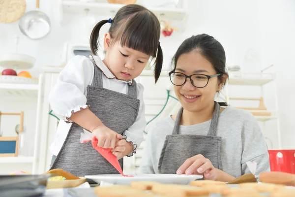 Asiático Kid e jovem mãe decorar biscoitos . — Fotografia de Stock