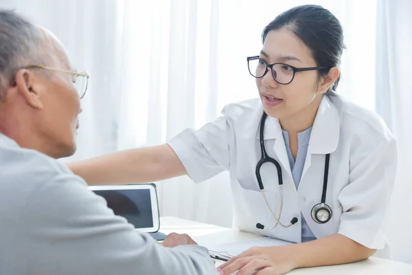 Médico femenino tranquilizando a paciente masculino mayor . — Foto de Stock