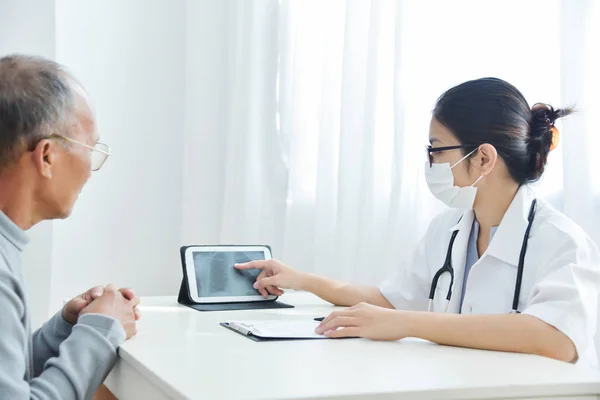 Asiática mujer médico discutir con senior hombre paciente . — Foto de Stock