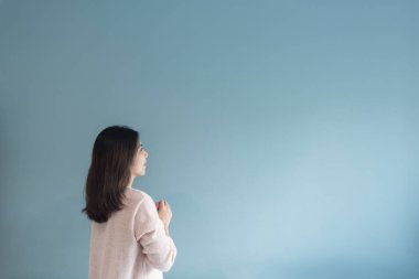 Asyalı kadın mavi duvara bakarak. 