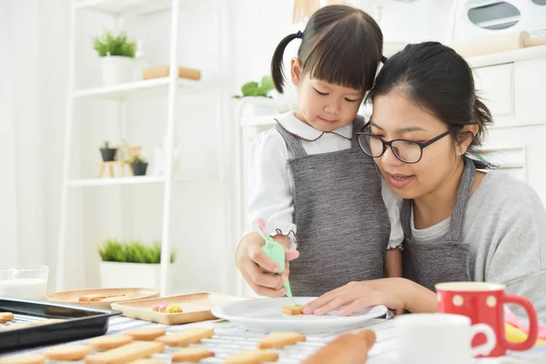 Asiático Kid e jovem mãe decorando biscoito . — Fotografia de Stock