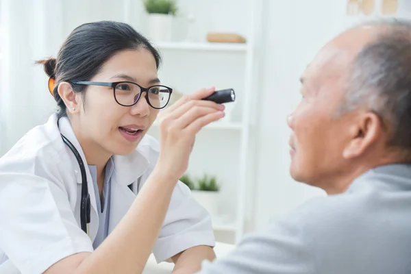 Dokter wanita memeriksa mata pasien pria senior. . — Stok Foto