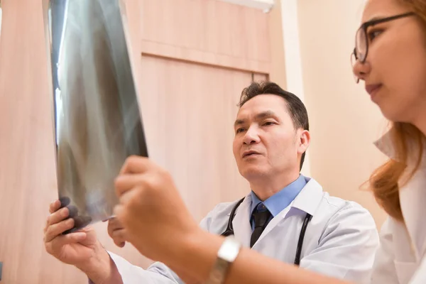 Médicos asiáticos examinando filme de raios X de um paciente . — Fotografia de Stock