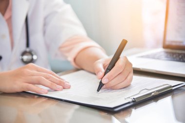 kadın doktor dizüstü bilgisayar kullanma ve bir şey panosuna yazma