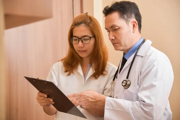 Ásia sênior masculino e feminino médicos segurando um clipboard . — Fotografia de Stock