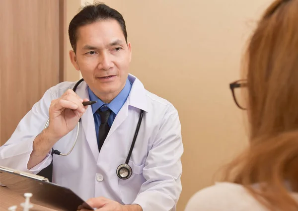 Азіатський старший чоловічого лікар розмовляти з пацієнтки. — стокове фото