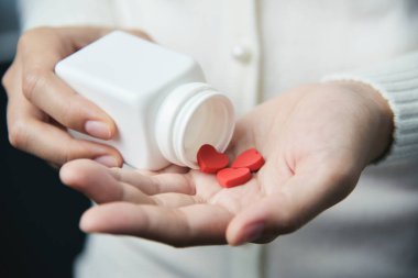 Eller hea içinde holding beyaz hap şişesi ve kırmızı hapları