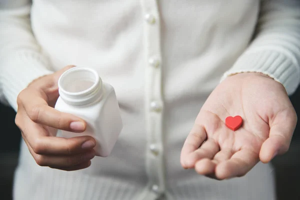 Les mains de la femme tient une bouteille de pilule blanche et une pilule rouge dans il — Photo