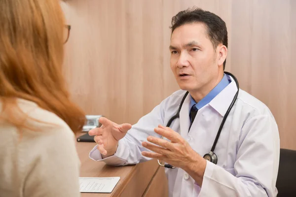 Azjatycka starszy mężczyzna lekarza dyskusji z pacjentka. — Zdjęcie stockowe