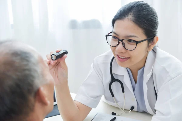 Médico feminino verificando para os olhos paciente homem sênior . — Fotografia de Stock