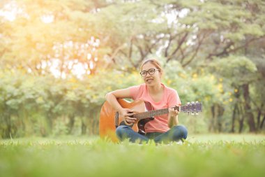 Kadın oturuyor ve akustik gitar çalmak.