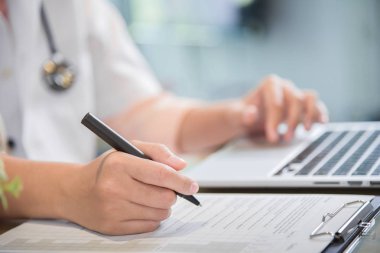 kadın doktor dizüstü bilgisayar kullanma ve bir şey panosuna yazma